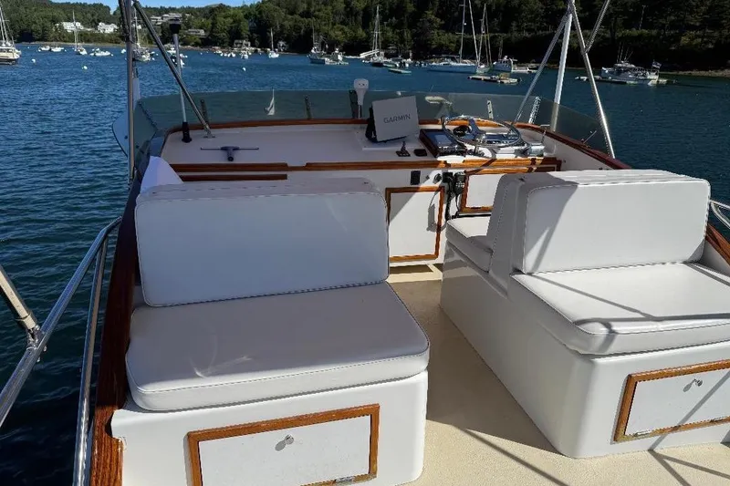 Slide: The Image of 1995 Wilbur Weekender boat interior with white seating, wooden accents, and scenic marina view. - 8