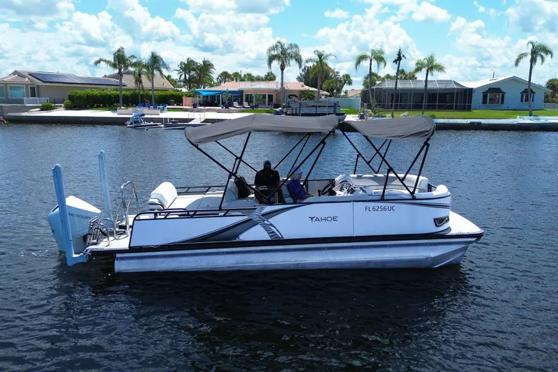 The Image of 2025 Tahoe Pontoon LTZ 23 on a sunny day, cruising near waterfront homes. - 0