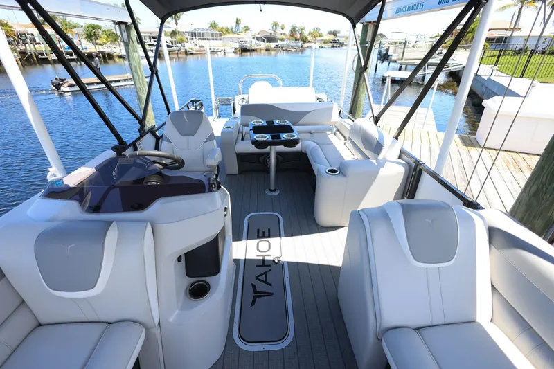 Slide: The Image of 2025 Tahoe Pontoon LTZ 23 interior with luxurious seating and modern helm, docked by a scenic waterfront. - 10