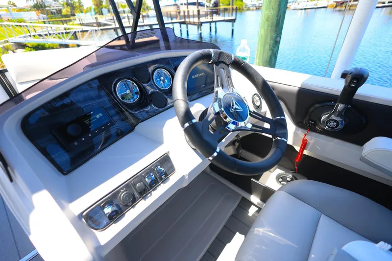 Slide: The Image of 2025 Tahoe Pontoon LTZ 23 dashboard with steering wheel and controls, docked by water. - 17