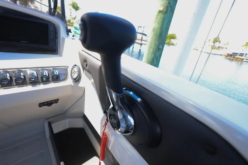 Slide: The Image of 2025 Tahoe Pontoon LTZ 23 boat dashboard with control lever and switches, docked by water. - 18