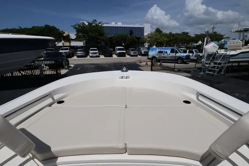 Slide: The Image of The image shows the bow of a 2027 Boston Whaler 210 Montauk. It features beige cushions and is set in a marina area with parked cars in the background. - 23