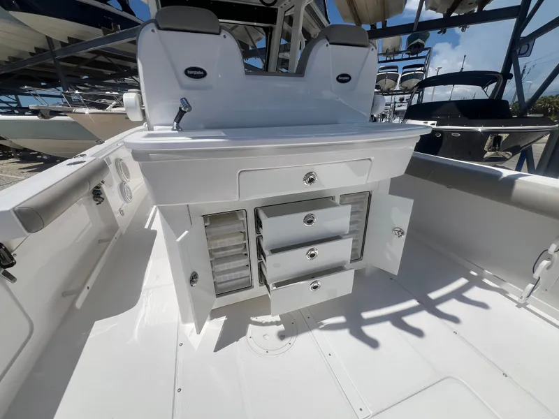 Slide: The Image of The image shows the cockpit of a 2019 Everglades 295 Center Console boat with open storage compartments. - 14