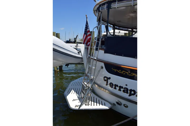 Slide: The Image of 1980 Cheoy Lee 52 Motorsailer with American flag and swim platform at dock. - 11