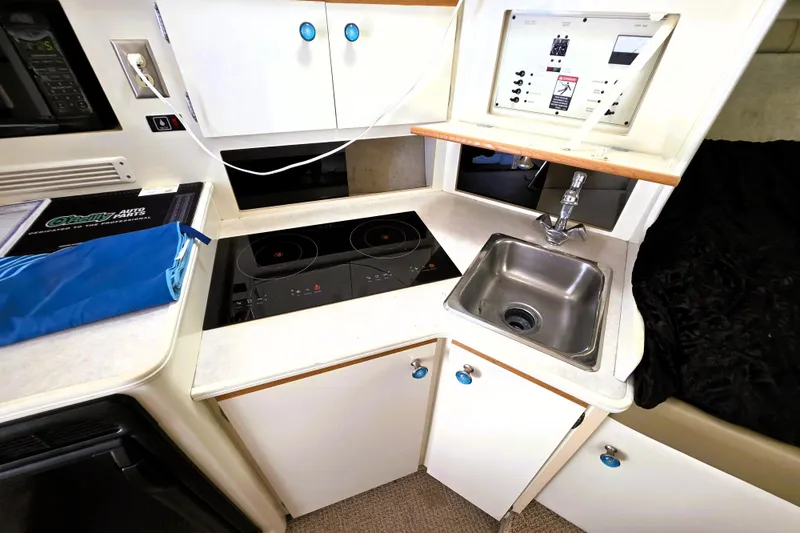Slide: The Image of Compact kitchen area in a 1999 Bayliner 3055 Ciera boat with stove and sink. - 12