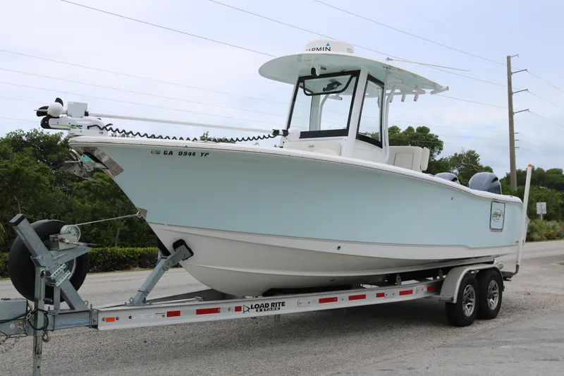Slide: The Image of 2023 Sea Hunt Gamefish 25 boat on trailer, light blue hull, parked outdoors. - 3