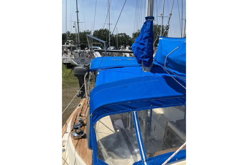 Slide: The Image of 1981 Pearson 365 Ketch sailboat with blue covers, docked among other boats. - 10