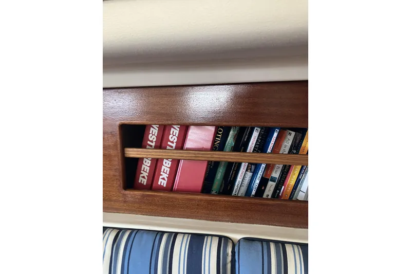 Slide: The Image of Bookshelf on 1981 Pearson 365 Ketch sailboat with striped cushion below. - 19