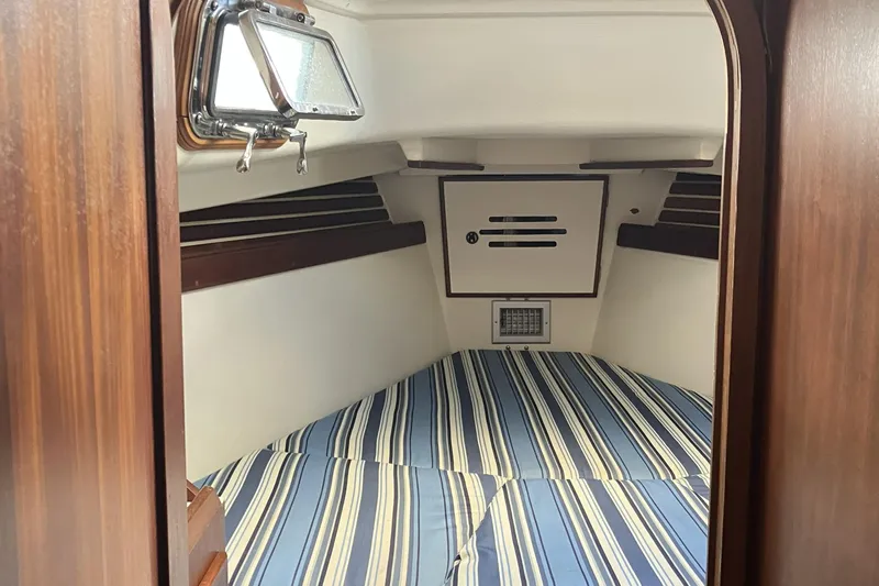 Slide: The Image of Interior cabin of 1981 Pearson 365 Ketch with striped bedding and wooden accents. - 21