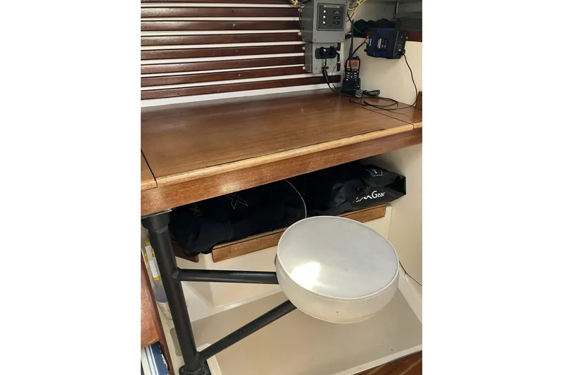 Slide: The Image of Navigation station inside a 1981 Pearson 365 Ketch sailboat, featuring a wooden desk and stool. - 25