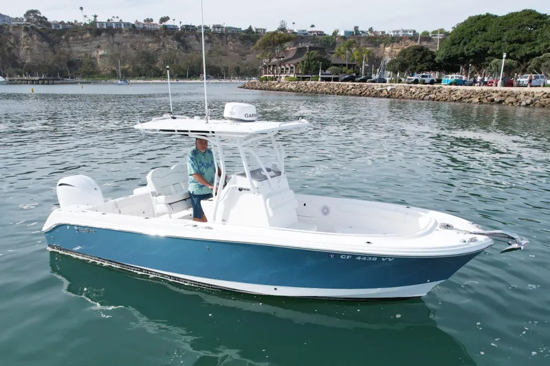 The Image of 2023 Edgewater 245CC boat on calm water, featuring a sleek blue and white design. - 0