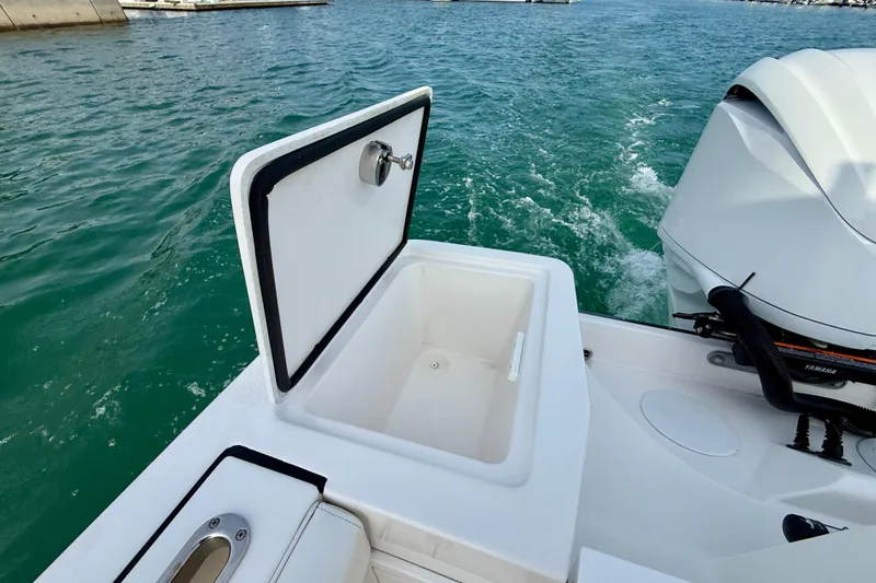 Slide: The Image of Open storage compartment on 2023 Edgewater 245CC boat, near outboard motor, on water. - 11