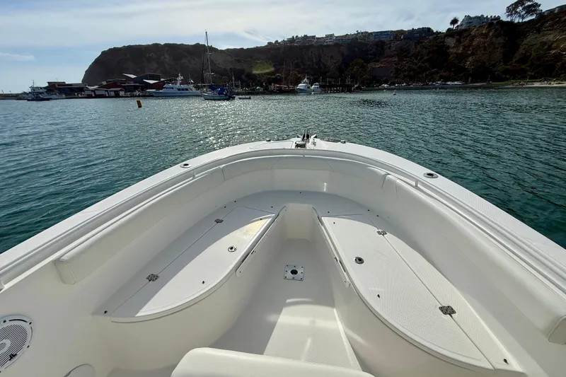Slide: The Image of Edgewater 245CC 2023 boat on calm water with scenic coastal backdrop. - 13