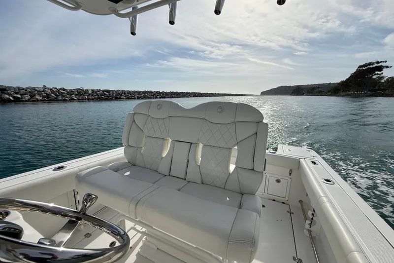 Slide: The Image of 2023 Edgewater 245CC boat interior with white seating, steering wheel, and ocean view. - 23