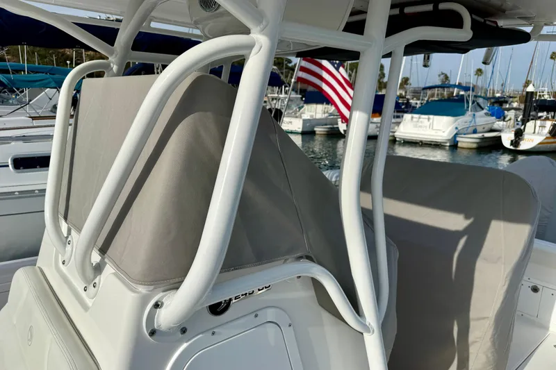 Slide: The Image of 2023 Edgewater 245CC boat interior with protective covers, docked in a marina. - 36