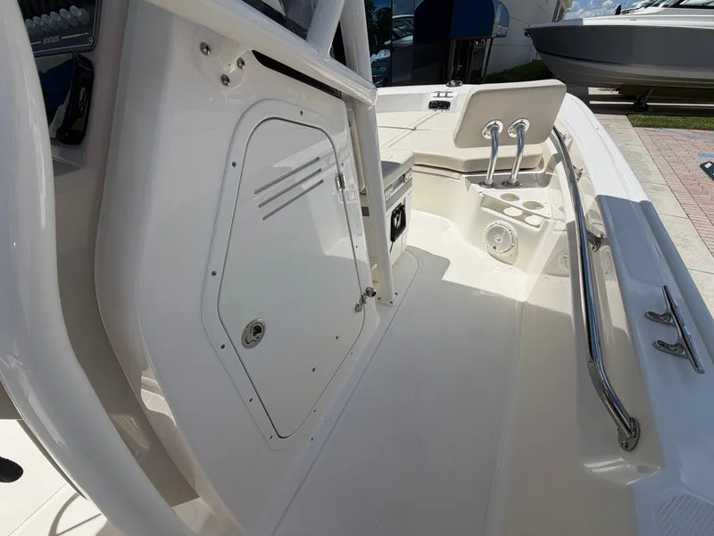 Slide: The Image of The image shows the deck of a Boston Whaler 210 Montauk boat. It features a white surface with a storage compartment and stainless steel railings. - 23