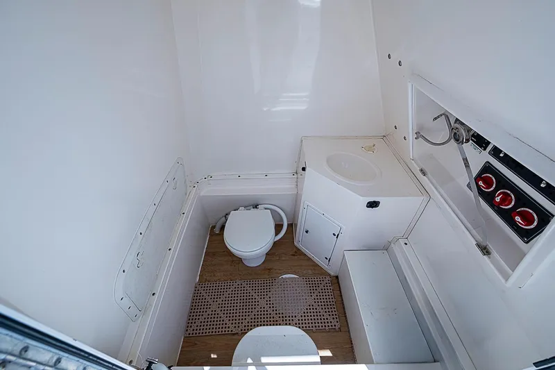 Slide: The Image of 2008 Buddy Davis 34 Center Console boat bathroom with toilet, sink, and control panel. - 6
