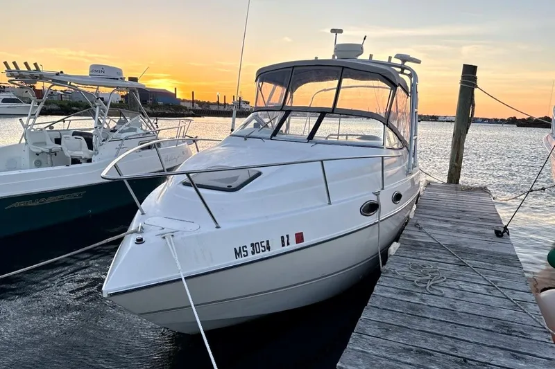 Slide: The Image of 2001 Stingray 240 CS boat docked at sunset, with a scenic waterfront view. - 2
