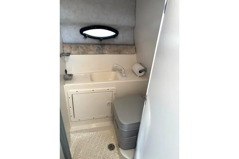 Slide: The Image of 2001 Stingray 240 CS boat bathroom with sink, toilet, and porthole window. - 7
