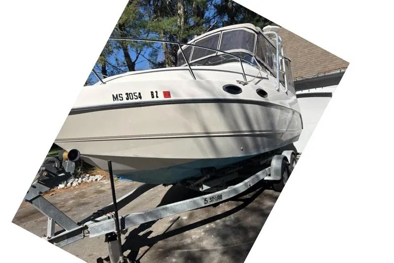 Slide: The Image of 2001 Stingray 240 CS boat on trailer, parked outdoors with trees in background. - 9