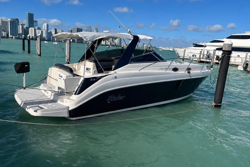 The Image of 2003 Rinker Fiesta Vee 342 yacht docked in turquoise waters with city skyline backdrop. - 0