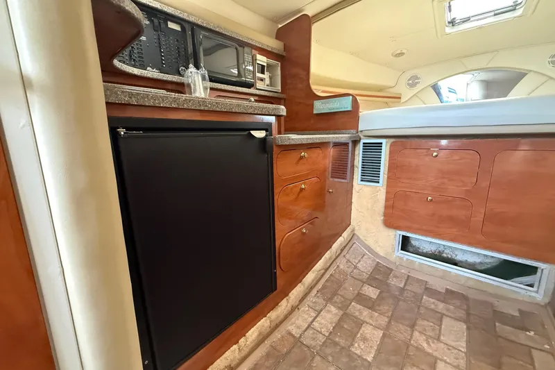 Slide: The Image of 2003 Rinker Fiesta Vee 342 cabin interior with kitchenette, featuring wood cabinetry and appliances. - 12