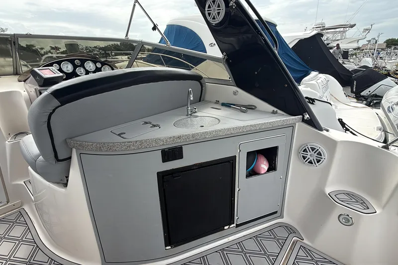 Slide: The Image of 2003 Rinker Fiesta Vee 342 boat interior with helm, sink, and storage compartments. - 2