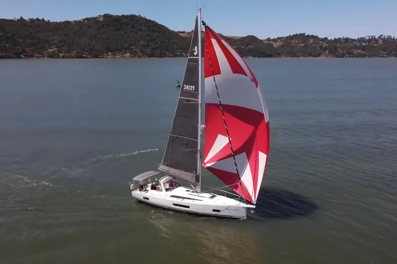 Slide: The Image of 2020 Beneteau Oceanis 46.1 sailing with vibrant red and white spinnaker on calm waters. - 37