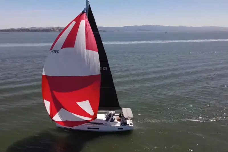 Slide: The Image of 2020 Beneteau Oceanis 46.1 sailing with vibrant red and white spinnaker on open water. - 5