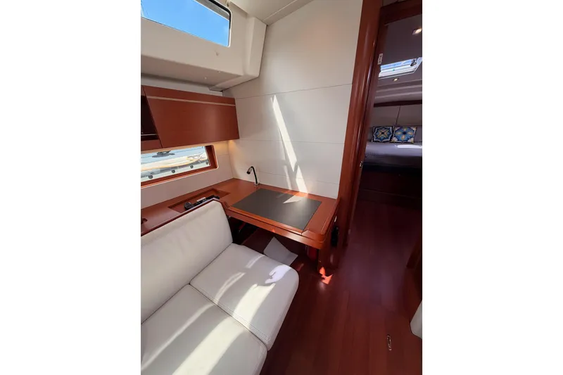 Slide: The Image of Interior of 2020 Beneteau Oceanis 46.1 yacht, featuring a cozy seating area and desk. - 88