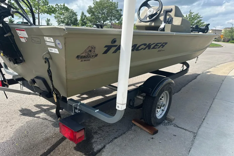 Slide: The Image of 2024 Tracker Grizzly 1648 SC boat on trailer, parked on a street. - 16