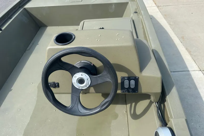 Slide: The Image of Steering console of 2024 Tracker Grizzly 1648 SC boat with cup holder and controls. - 18