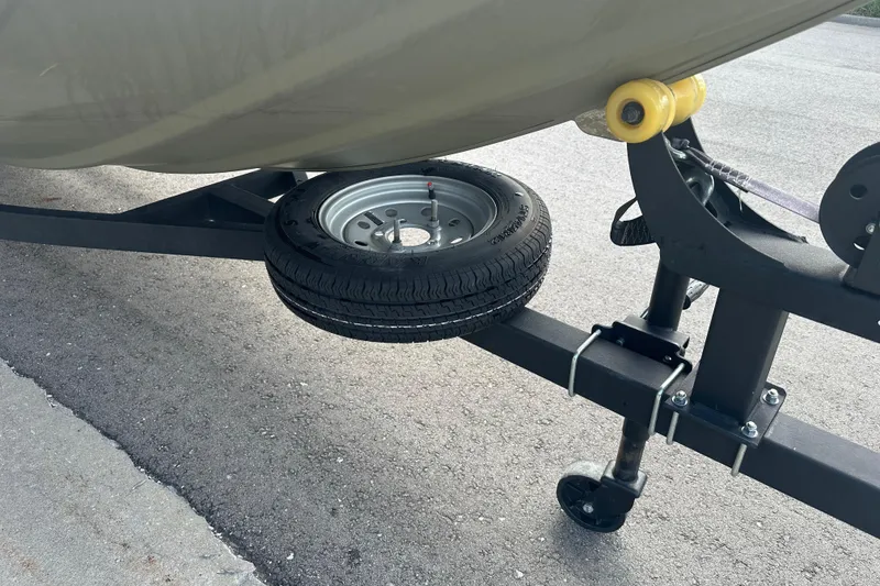 Slide: The Image of 2024 Tracker Grizzly 1648 SC trailer with spare tire on asphalt. - 22