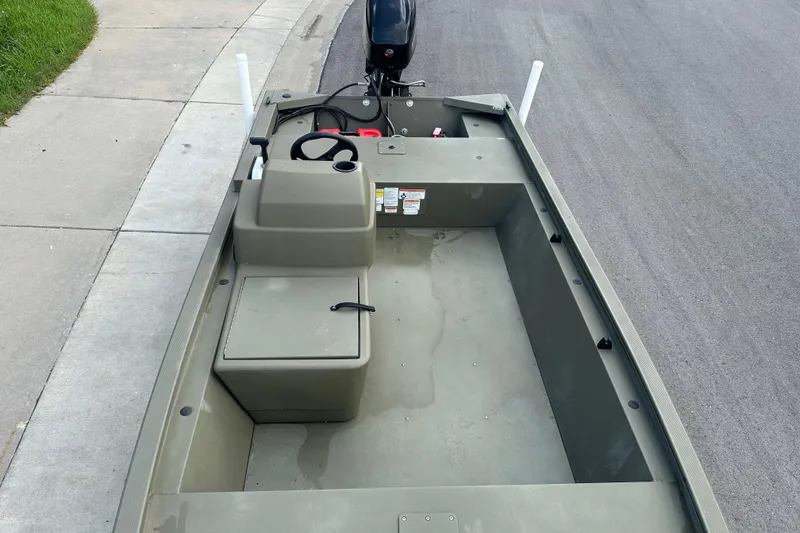 Slide: The Image of 2024 Tracker Grizzly 1648 SC boat interior with steering console and storage, parked on pavement. - 30