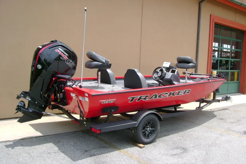 Slide: The Image of 2026 Tracker Pro Team 190 boat, red exterior, parked on a trailer outside a building. - 2