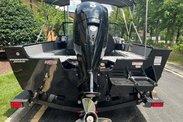Slide: The Image of 2026 Tracker Pro Guide V-175 WT boat, rear view with outboard motor, parked outdoors. - 3