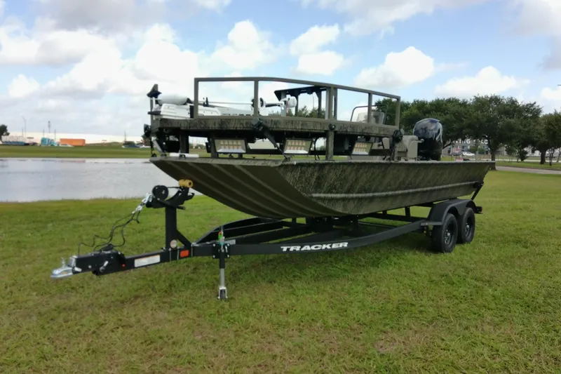 Slide: The Image of 2026 Tracker Grizzly 2072 CC Sportsman boat on trailer, parked on grass near water. - 76