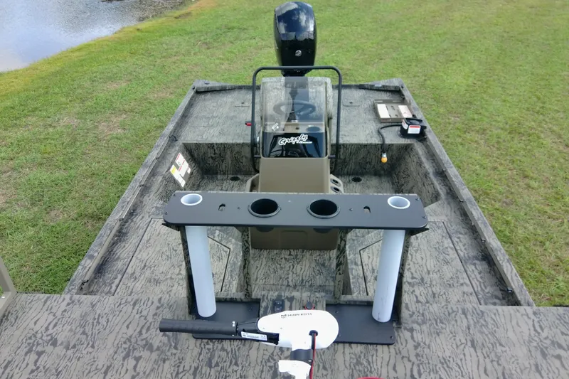 Slide: The Image of 2026 Tracker Grizzly 2072 CC Sportsman boat interior with steering console and fishing rod holders. - 85