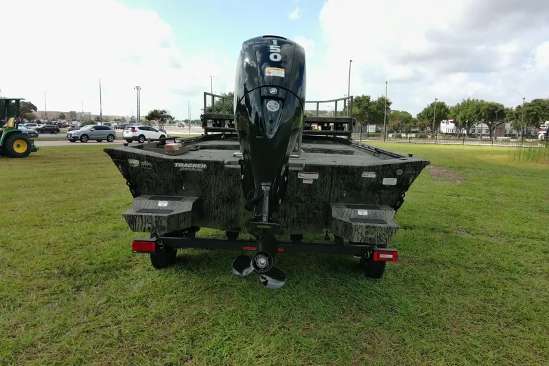 Slide: The Image of 2026 Tracker Grizzly 2072 CC Sportsman boat, rear view on grassy field. - 79
