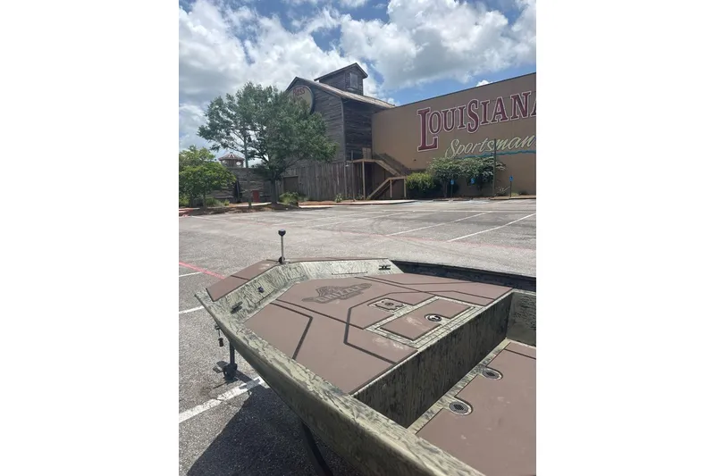 Slide: The Image of 2026 Tracker Grizzly 1860 CC boat parked near Louisiana Sportsman building under a cloudy sky. - 4
