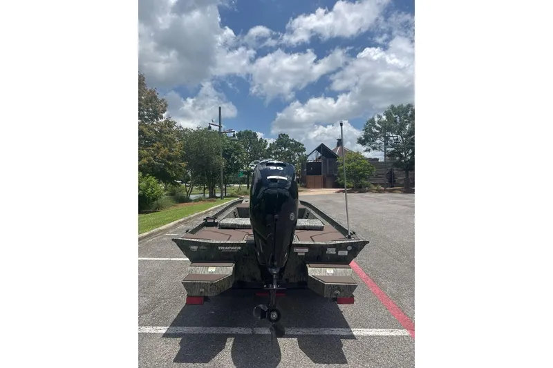 Slide: The Image of 2026 Tracker Grizzly 1860 CC boat with outboard motor in a parking lot. - 3