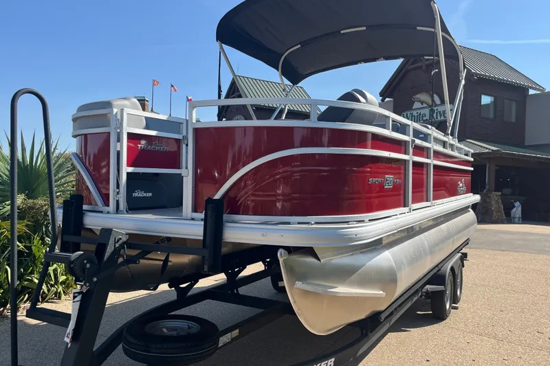 The Image of 2026 Sun Tracker SportFish 20 DLX pontoon boat on trailer, red and silver design. - 0