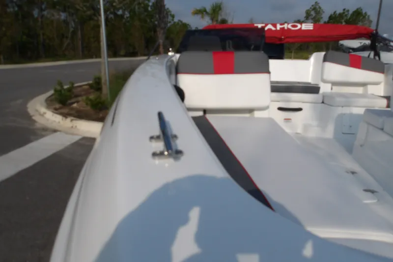 Slide: The Image of 2026 Tahoe T18 boat with red and gray seating, parked near a road. - 6