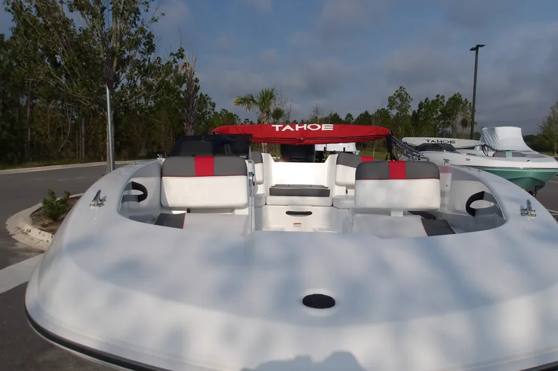 Slide: The Image of 2026 Tahoe T18 boat with red and gray seating, parked outdoors. - 19