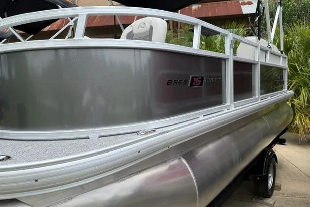 Slide: The Image of 2026 Sun Tracker Bass Buggy 16 XL Select pontoon boat, silver exterior, docked outdoors. - 3