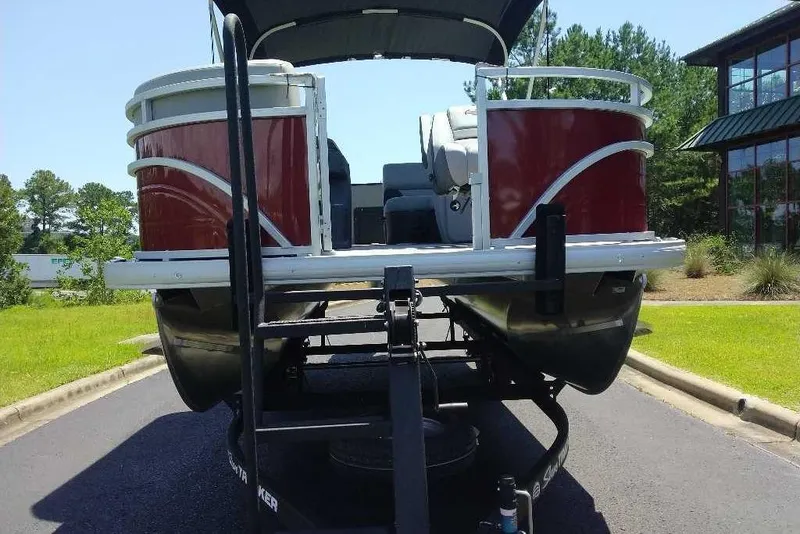 Slide: The Image of 2026 Sun Tracker SportFish 20 DLX pontoon boat on trailer, parked outdoors. - 2