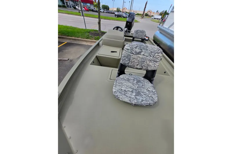 Slide: The Image of 2026 Tracker Grizzly 1754 SC boat with camo seats, parked outdoors. - 3