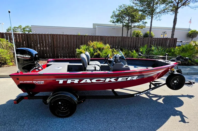 The Image of 2026 Tracker Super Guide V-16 SC boat on trailer, red exterior, parked outdoors. - 0