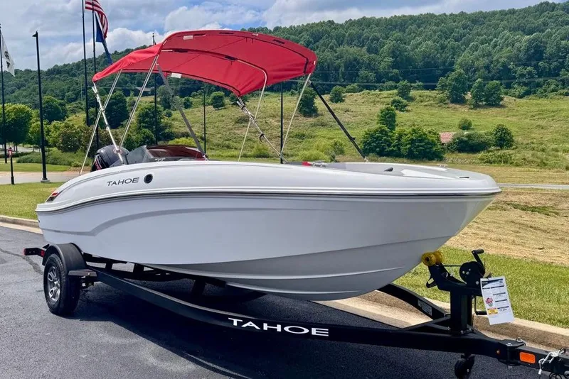 Slide: The Image of 2026 Tahoe T18 boat with red canopy on trailer, parked outdoors. - 2