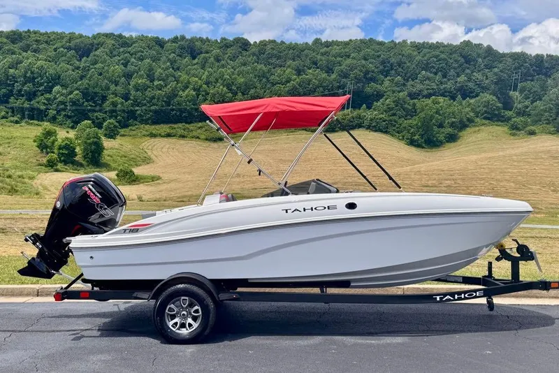The Image of 2026 Tahoe T18 boat with red canopy on trailer, set against scenic countryside. - 0